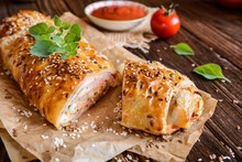 Savory strudel with ham, cheese, tomato sauce and herbs