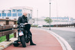 © Connect Images - Mature male motorcyclist sitting on roadside using laptop