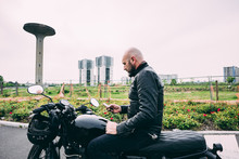 Mature Male Motorcyclist Sitting On Motorcycle Reading Smartphone Text