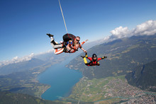 Smiling Tandem Sky Divers Holding Hand With Free Faller, Interlaken, Berne, Switzerland