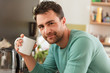 © Connect Images - Portrait of man holding coffee cup looking at camera smiling