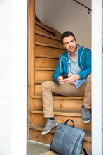 Man With Briefcase Sitting On Wooden Stairway Holding Phone
