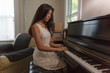 © Connect Images - Teenage girl sitting playing piano in dining room