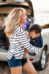 Wall Mural - Beautiful woman with a child of four years in the car are going to have a trip