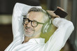 © Westend61 - Portrait of smiling man with grey hair and beard listening music with headphones