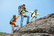 A Family Of Three Climbing Up The Top Of A Mountain Holding Hands