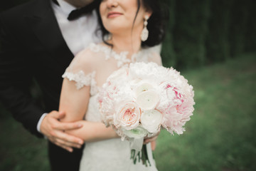 Perfect wedding couple holding luxury bouquet of flowers