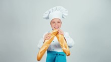 Happy Baker Girl 7-8 Years Child Breaks Bread Baguette And Gives You It At Camera And Smiling
