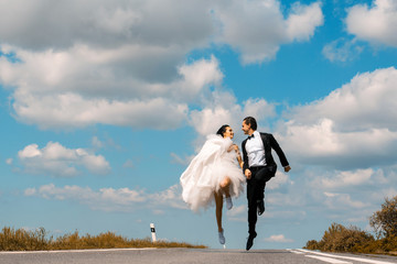 Wall Mural - wedding happy couple running on road