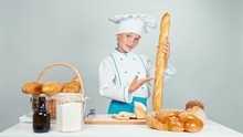 Baker Girl 7-8 Years Child Gives You Bread Baguettes And Smiling At Camera Isolated On White