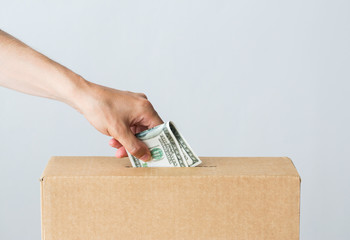 man putting dollar money into donation box