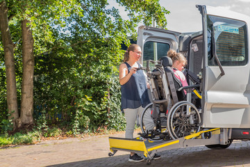 Working together with disability / Disability a disabled child in a wheelchair being cared for by a voluntary care worker