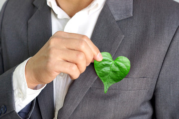 businessman holding a green heart leaf / business with corporate social responsibility and environme