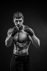 Wall Mural - Handsome male model posing at studio in front of a black background.