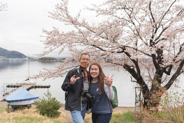 Elder asian man with camera on his neck hold young asian lady wi