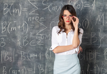 young smart sexy woman in eyeglasses near blackboard with math calculations