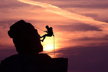 man rock climber silhouette over bright sunset