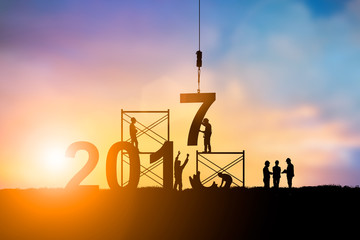 Wall Mural - Silhouette employees work as a team to change the 6 to 7, 2017 Happy New Year background 
