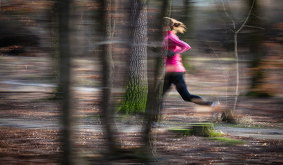 Wall Mural - Young woman running outdoors in a city park on a cold fall/winte