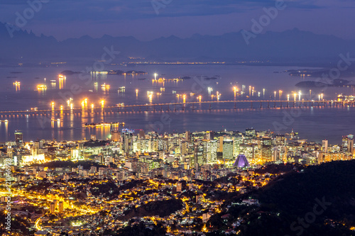 Aerial view of Rio de Janeiro downtown by night. Rio-Niteroi Bridge spans Gua...