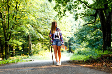 Young female with map hiking trough forest on beautiful summer day.