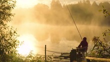 Fisherman At Sunrise Fishing On The Float Rod.