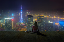 Woman Sitting On The Roof With Coffee Cup And Enjoing View On Night Shanghai.