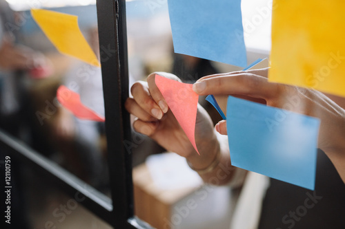 Fotomural Hands of woman sticking adhesive notes on glass