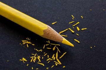 yellow wooden pencil on black paper background