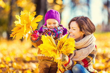 Little girl playing with mother in the autumn park