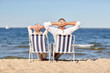 © Syda Productions - senior couple sitting on chairs at summer beach
