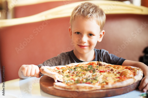 Plakat Urocza chłopiec łasowania pizza przy restauracją