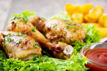 Poster - Roast chicken drumsticks and chips on wooden table

