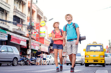 Wall Mural - Travel and tourism. Couple of backpackers walking together on asian street.