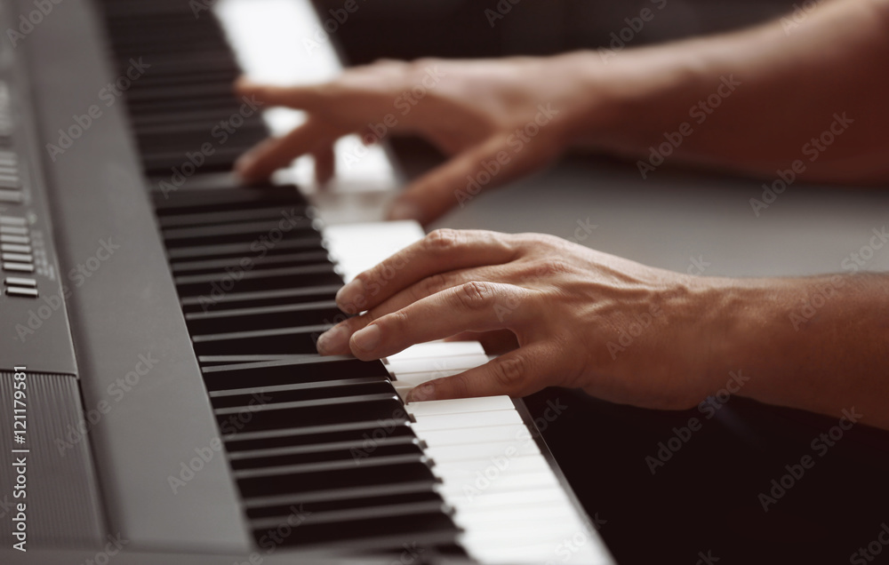 Male hands playing on synthesizer