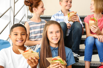 Schoolchildren eating sandwiches while sitting on stair-steps at school