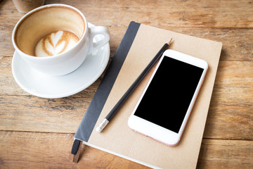 Mobile phone and diary notebook with coffee cup on wood backgrou