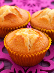 Wall Mural - Group of three cupcakes on brown background, close up, vertical