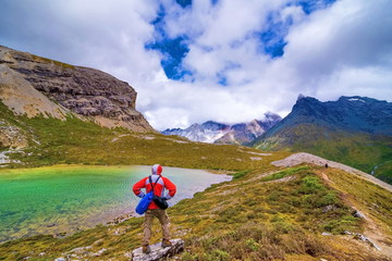 tourist visting autumn forest with mt. jambeyang and Lurong pasture in Yading national level reserve in Daocheng, Sichuan Province, China.