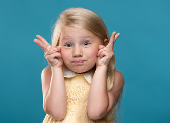 Wall Mural - Funny, pretty, young girl showing four fingers on a blue background