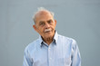 A senior Indian / South Asian man against a light blue background