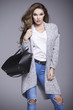 © dorriss - Beautiful young woman in a gray sweater and a black handbag