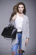 © dorriss - Beautiful young woman in a gray sweater and a black handbag
