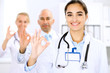 © rogerphoto - Happy doctor woman  with medical staff at the hospital. Thumbs up and Ok sign!