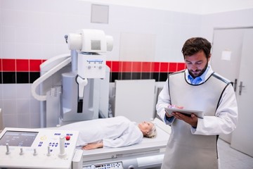 Poster - Doctor using digital tablet and patient lying on x ray machine