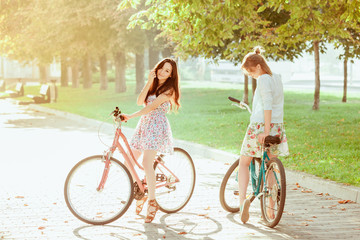 Wall Mural - The two young girls with bicycles in park