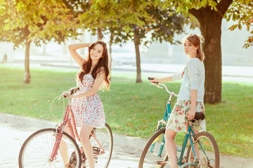 Wall Mural - The two young girls with bicycles in park