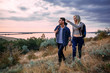 © kurapatka - Young caucasian couple hiking outdoors with backpacks during sunset