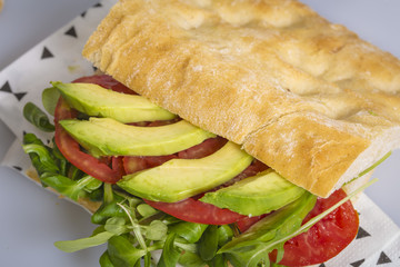 Vegan sandwich made of avocado, tomato and salad isolated on a white table background