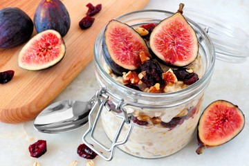 Wall Mural - jar of overnight autumn oats with red figs, cranberries and walnuts against a marble background